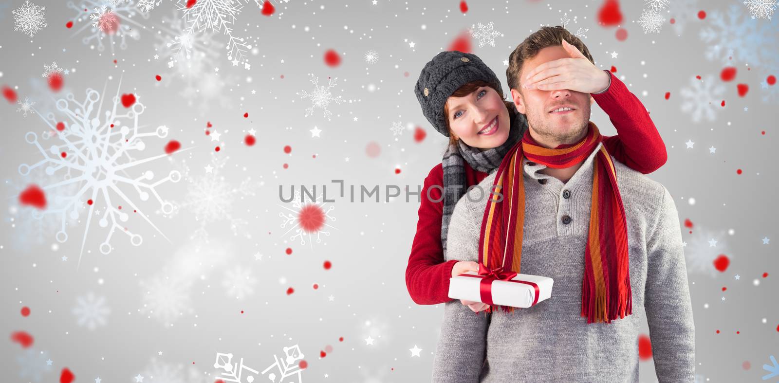 Woman giving man a present against snowflake pattern