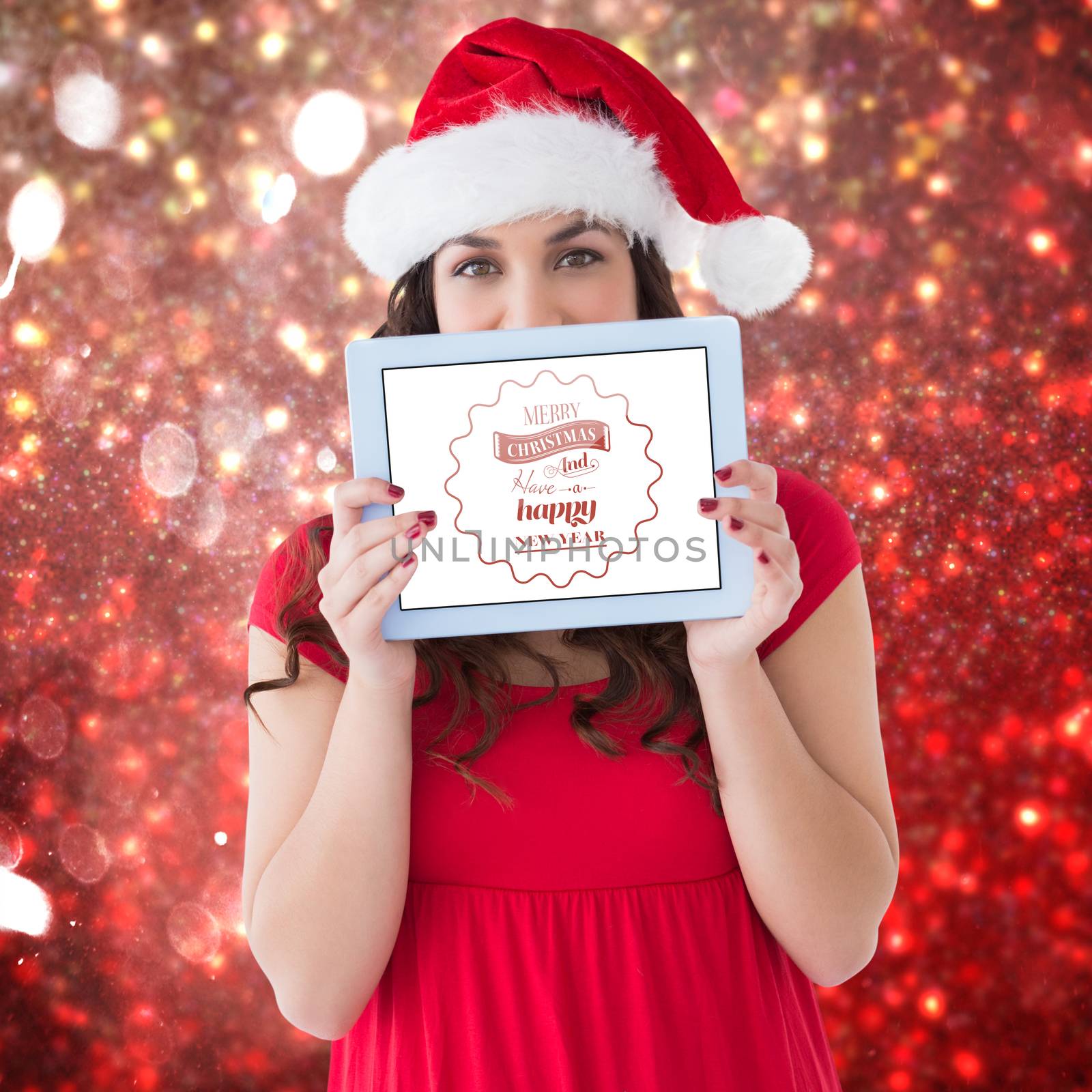Festive brunette showing a tablet  against white snow and stars on red