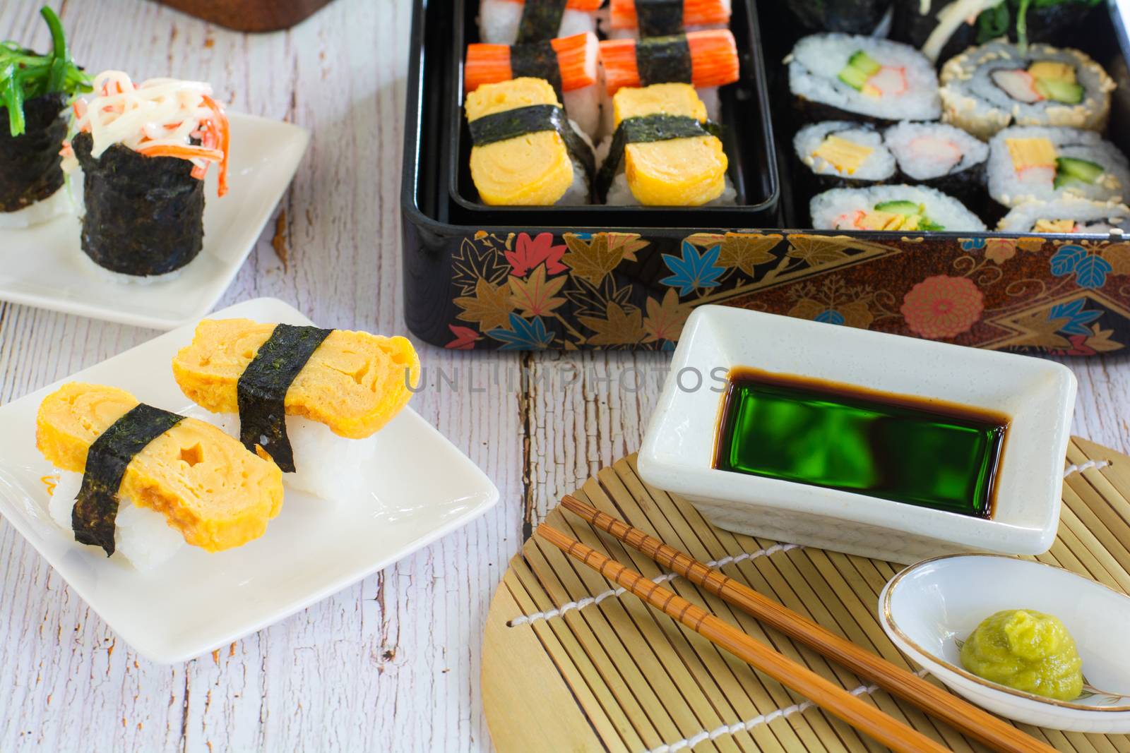 Set of variety sushi on white plate and bento box served with soy sauce and wasabi. Delicious japanese food.
