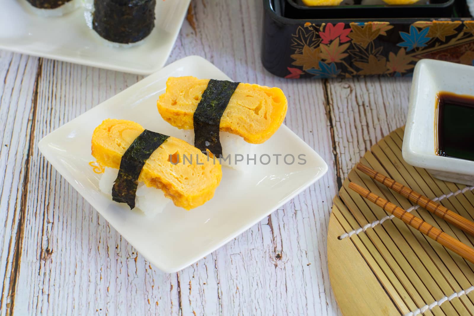 Tamagoyaki sushi or sweet egg on rice and seaweed wrap on square white plate. Delicious japanese food.