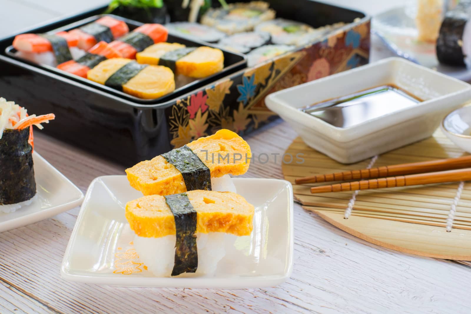 Tamagoyaki sushi or sweet egg on rice and seaweed wrap on square white plate. Delicious japanese food.