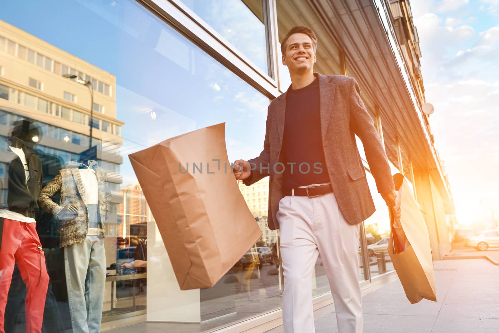 Serious cool guy with shopping paper bags walking at street.