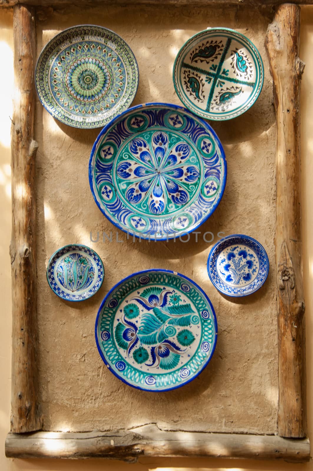 eastern ceramic plates hang on a clay wall. the wall of clay is decorated in an oriental style with a ceramic plate and wooden blocks