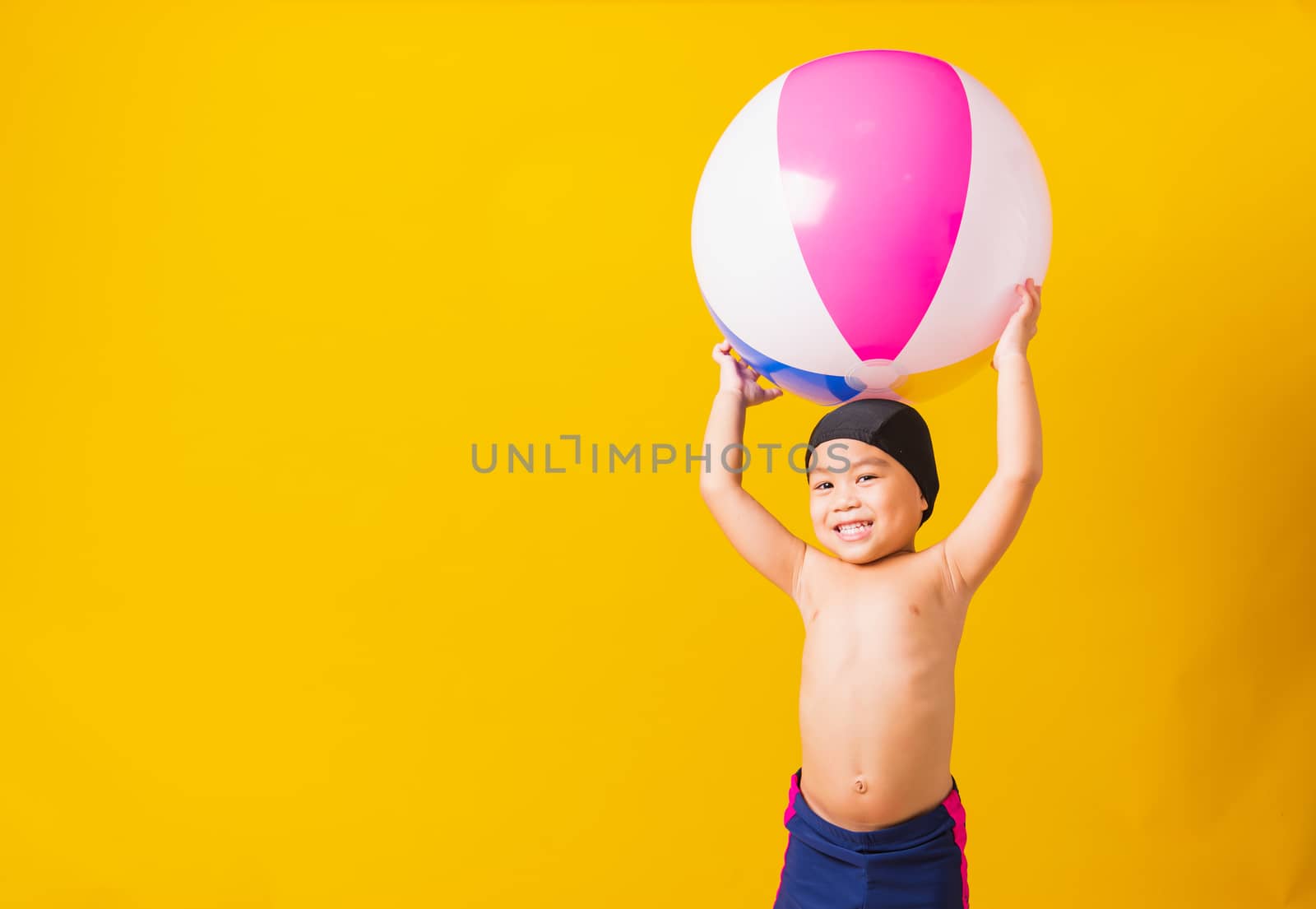 Child boy smiling in swimsuit hold beach ball by Sorapop