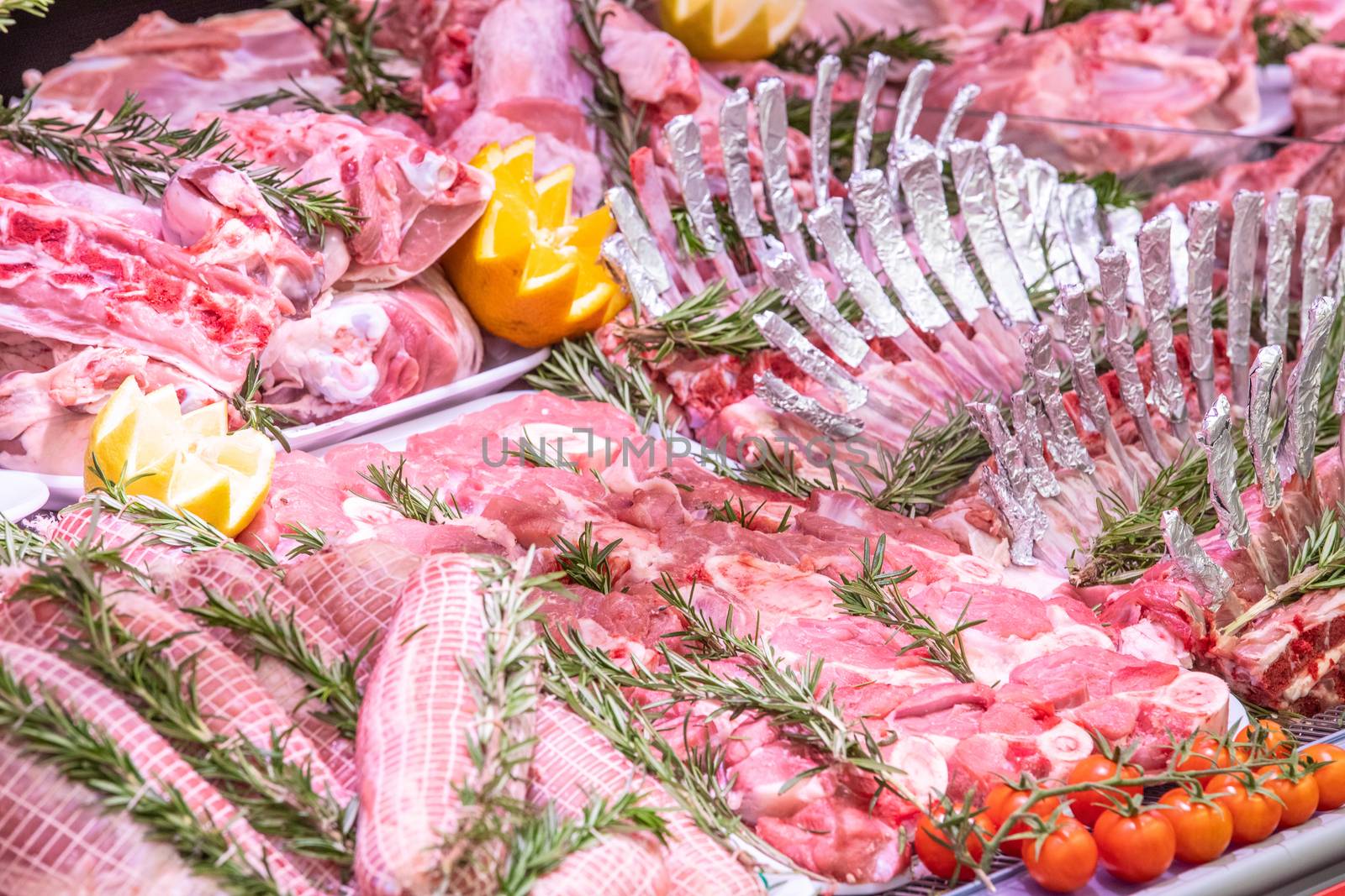 Meat department in butchery inside a mall. Various types of meat displayed in an orderly and creative way. Shelves of a food supermarket. Orange and vegetables for decoration and topping.