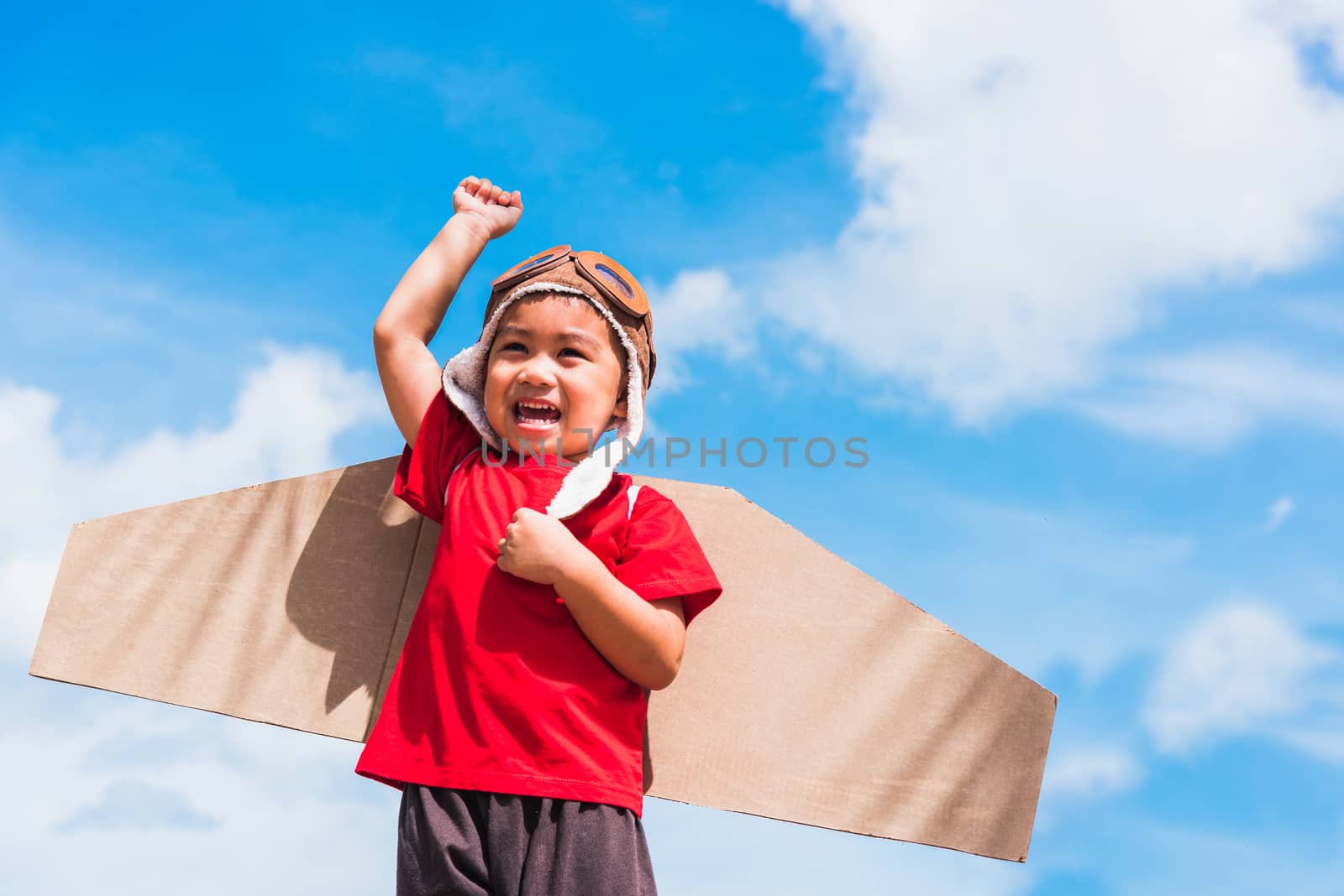 Kid little boy smile wear pilot hat play with toy airplane wing  by Sorapop