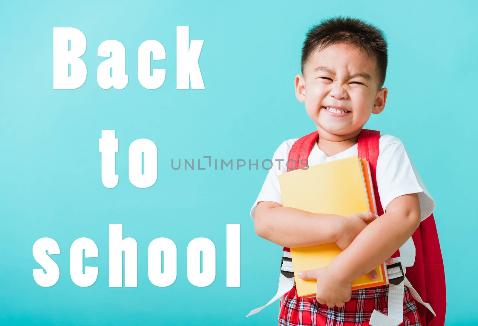 Back to school concept. Portrait Asian happy funny cute little child boy smiling and laugh hug books, studio shot isolated blue background. Kid from preschool kindergarten with school bag education