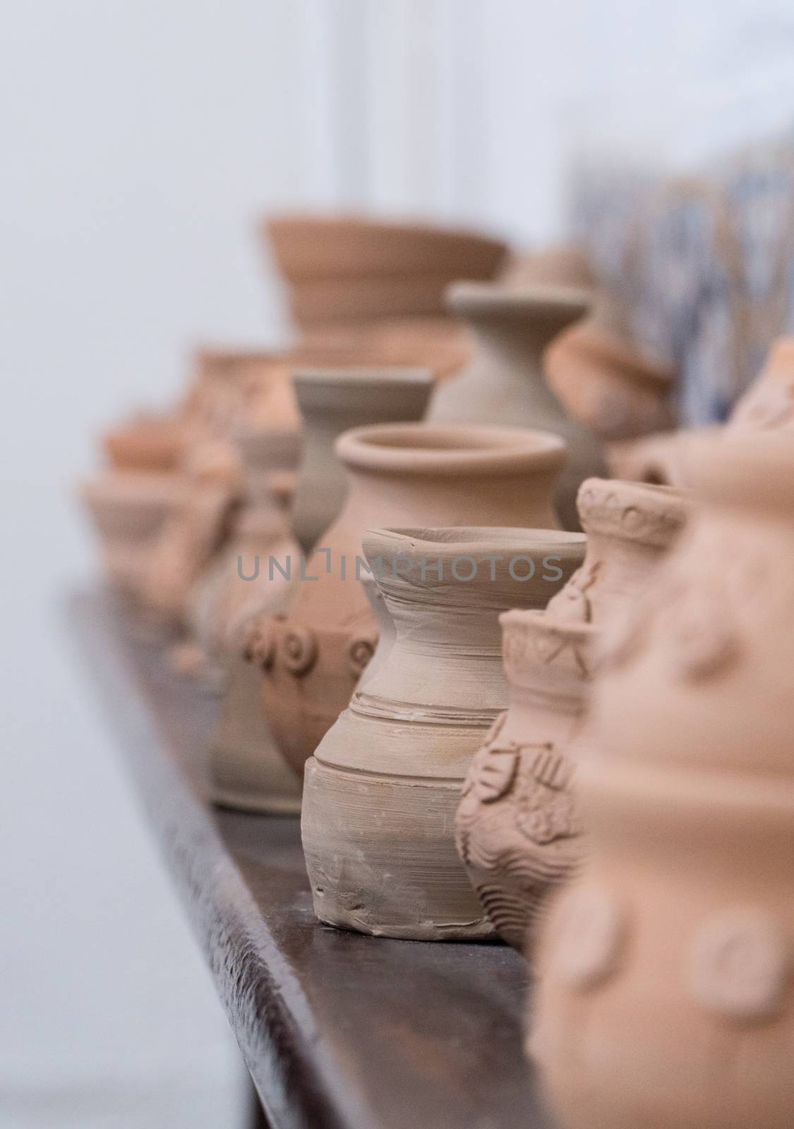 row of clay pots on the shelf, blurred background. children's crafts