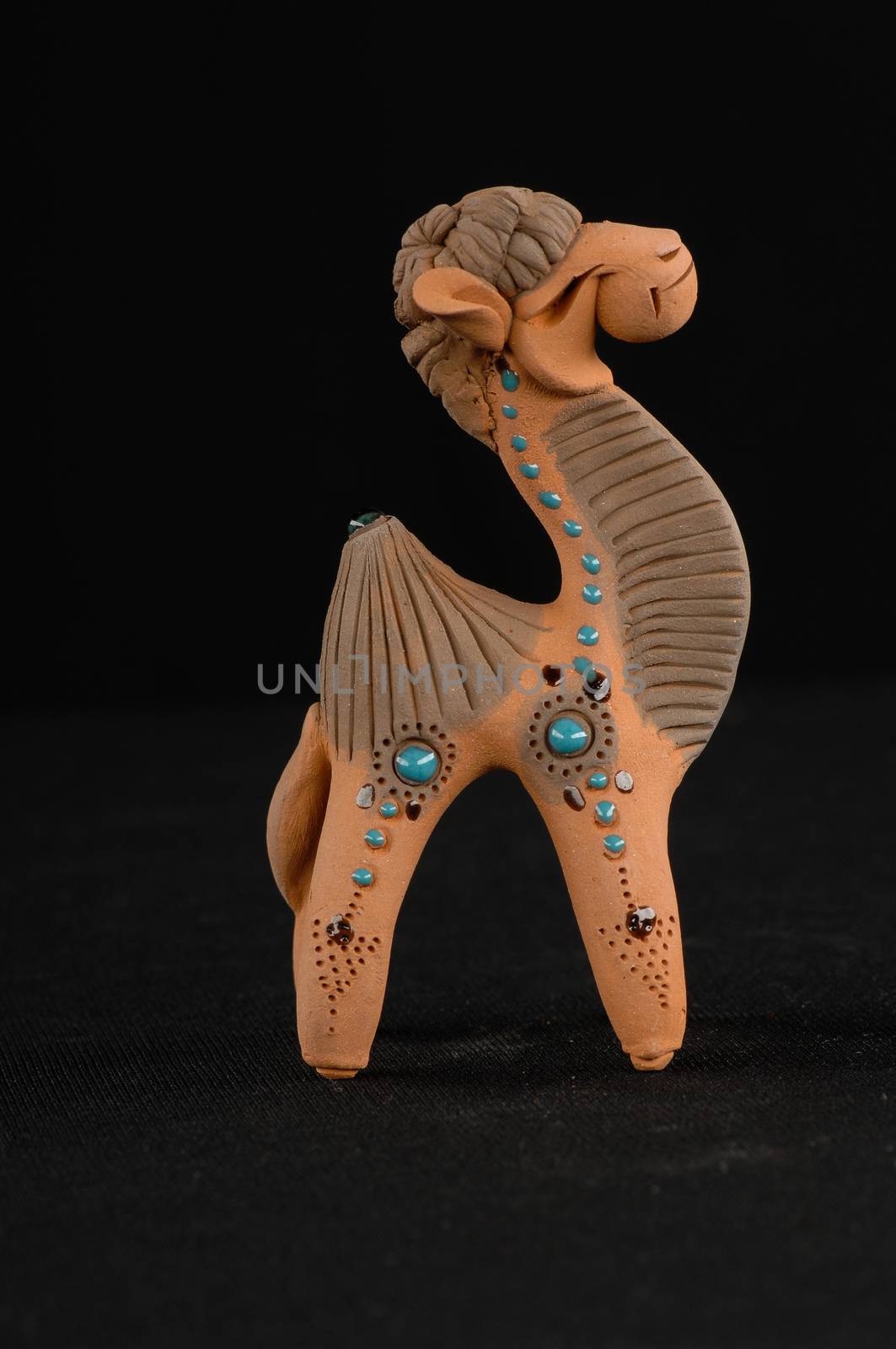 Asian and Oriental painted toy from burnt clay in the form of a camel on a black background
