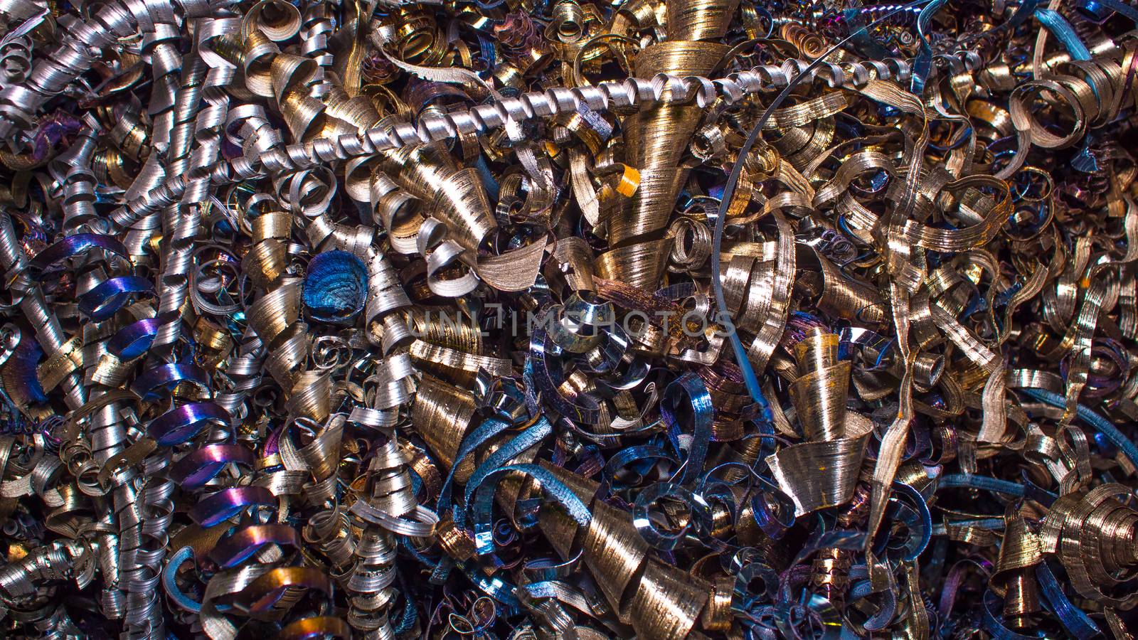 Metal background. Abstract color background of metal shavings. Wallpaper or screensaver of colored metallic chips. Processing of ferrous and non-ferrous metals in a factory or plant. Colored shavings. 