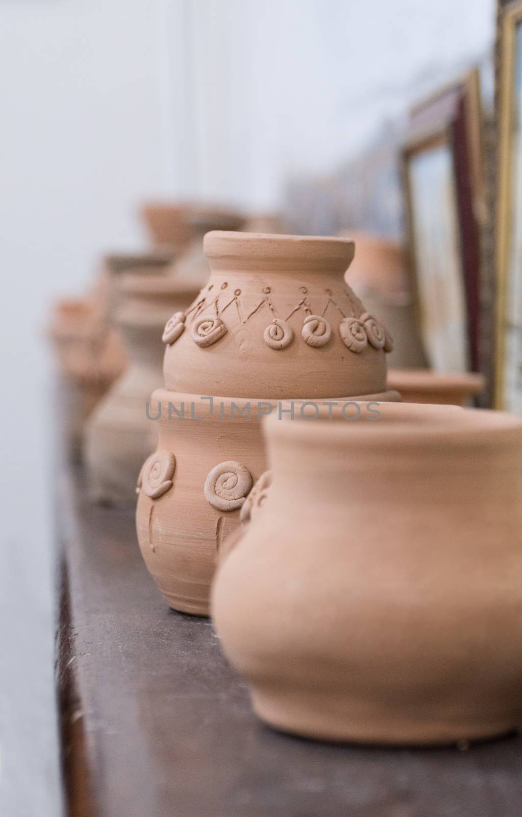 row of clay pots on the shelf, blurred background. children's crafts