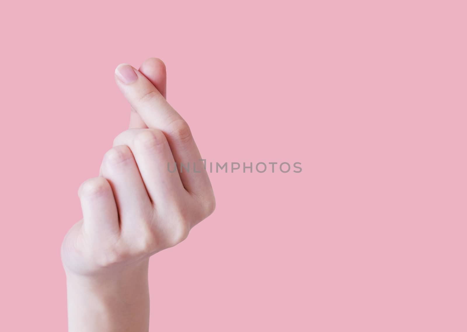 Love concept of Young woman hand making mini heart on pink background with copy space