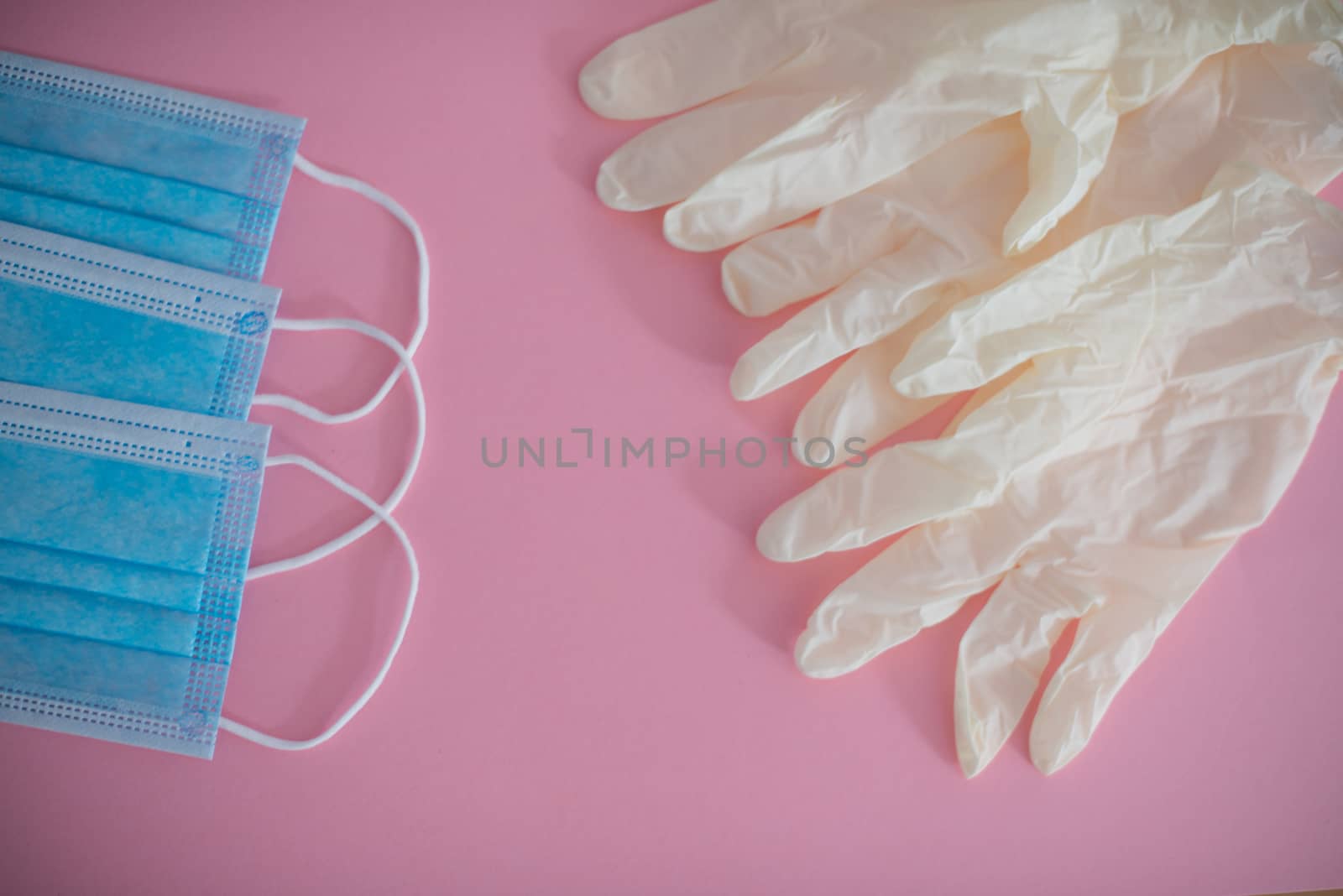 Latex gloves and face mask isolated against pink background