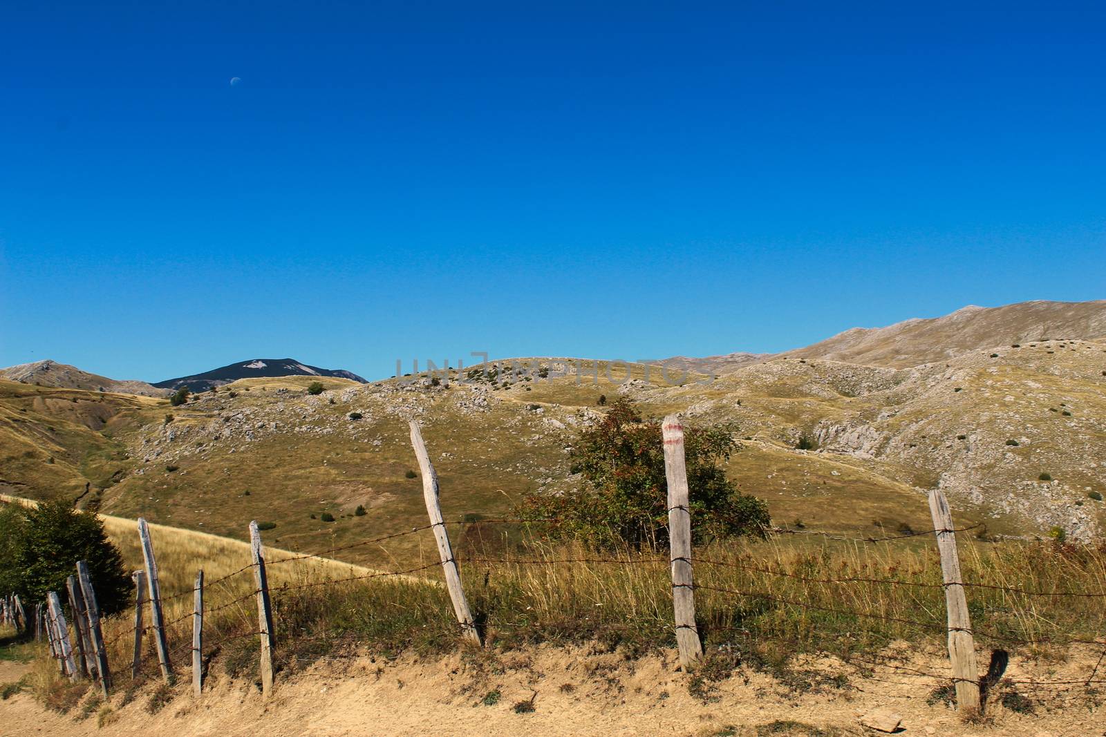 Picture from the old mountain road. Over an old wire fence a mountain hill without vegetation. Autumn view of Bjelasnica mountain, Bosnia and Herzegovina.