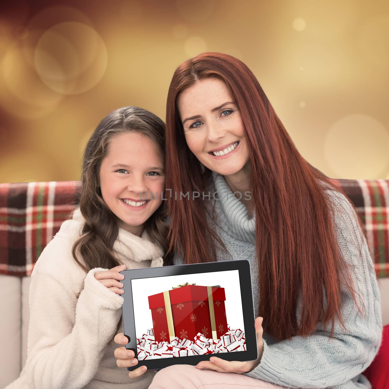 Mother and daughter showing tablet against orange abstract light spot design