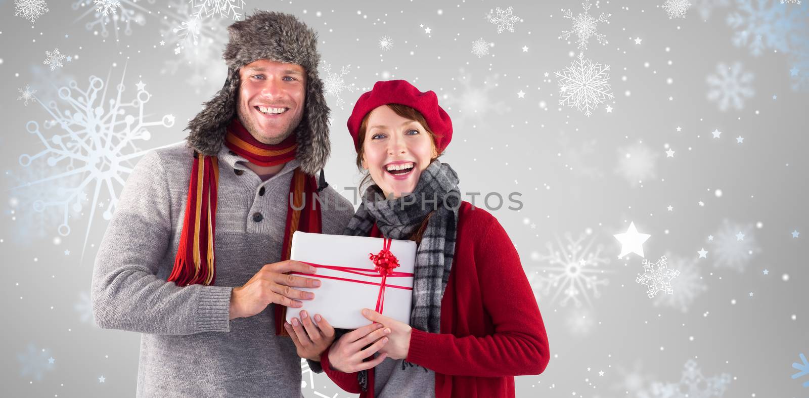 Couple smiling and holding gift against snowflake pattern