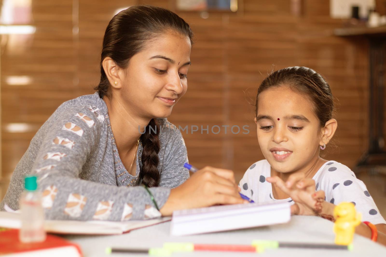 young girl teaching her sister at home - concept of homeschooling during coronavirus or covid-19 lockdown pandemic. by lakshmiprasad.maski@gmai.com