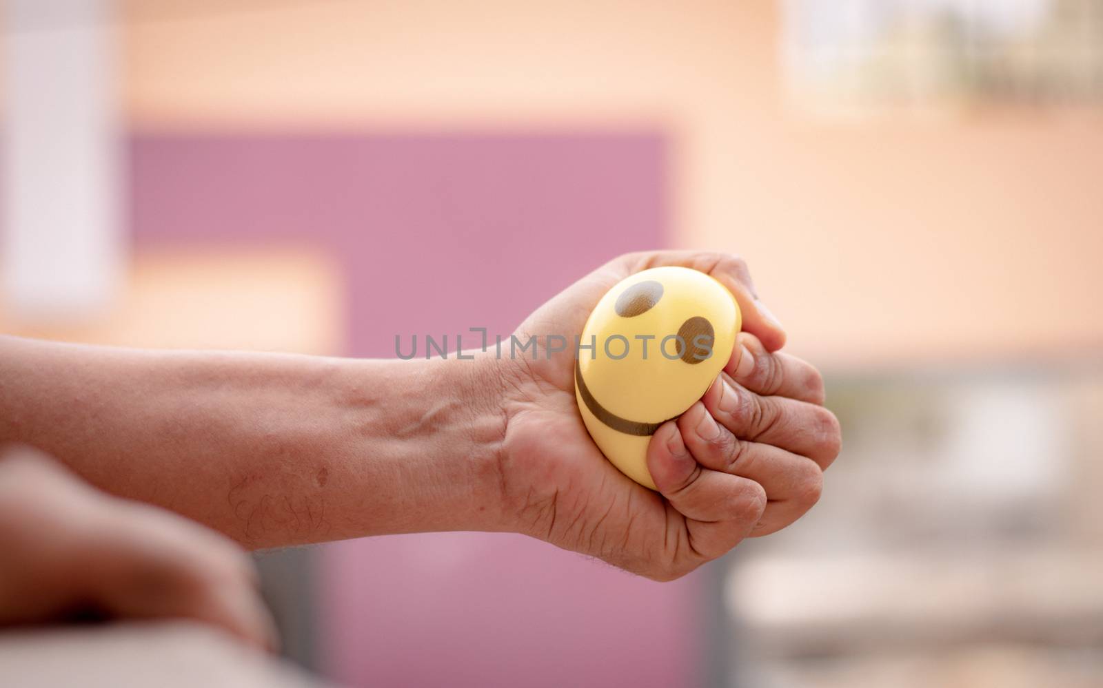 Hands squeezing or pressing stress ball at home to release stress - concept of stress buster by lakshmiprasad.maski@gmai.com