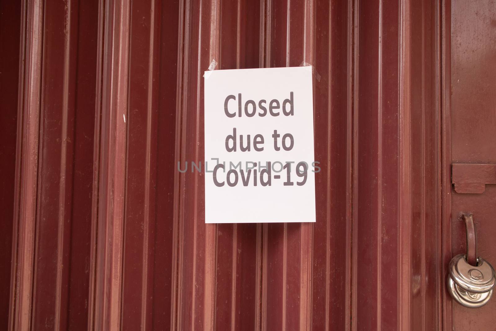 Closed due to coronavirus or covid-19 signage on Closed shutter door in front of shop or store due to coronavirus outbreak. by lakshmiprasad.maski@gmai.com