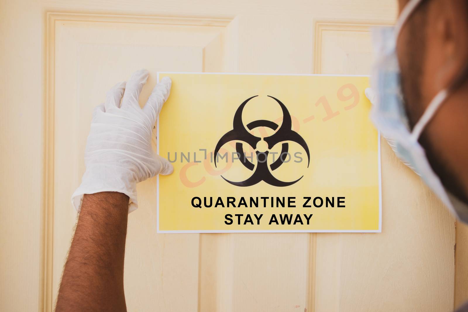 Frontline worker applying banner of Covid-19 or coronavirus quarantine zone stay away infront of the door at hospital as caution note