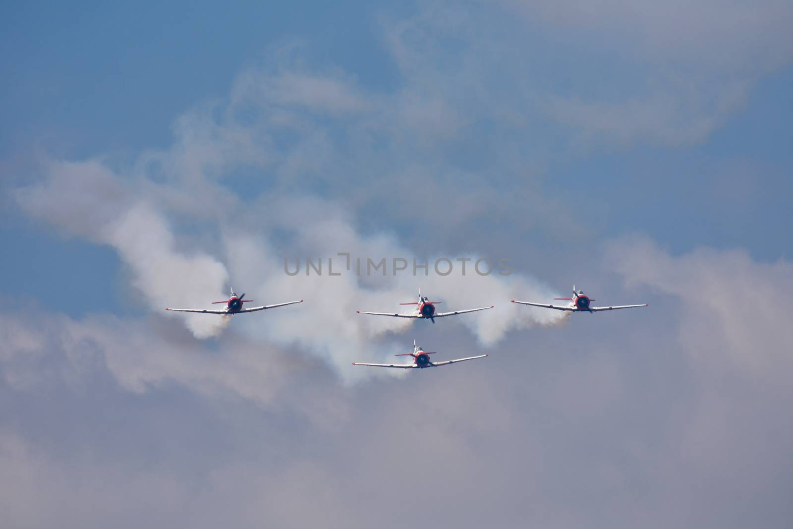 A flying formation of four harvard aircraft streaming smoke during an airshow display, Pretoria, South Africa