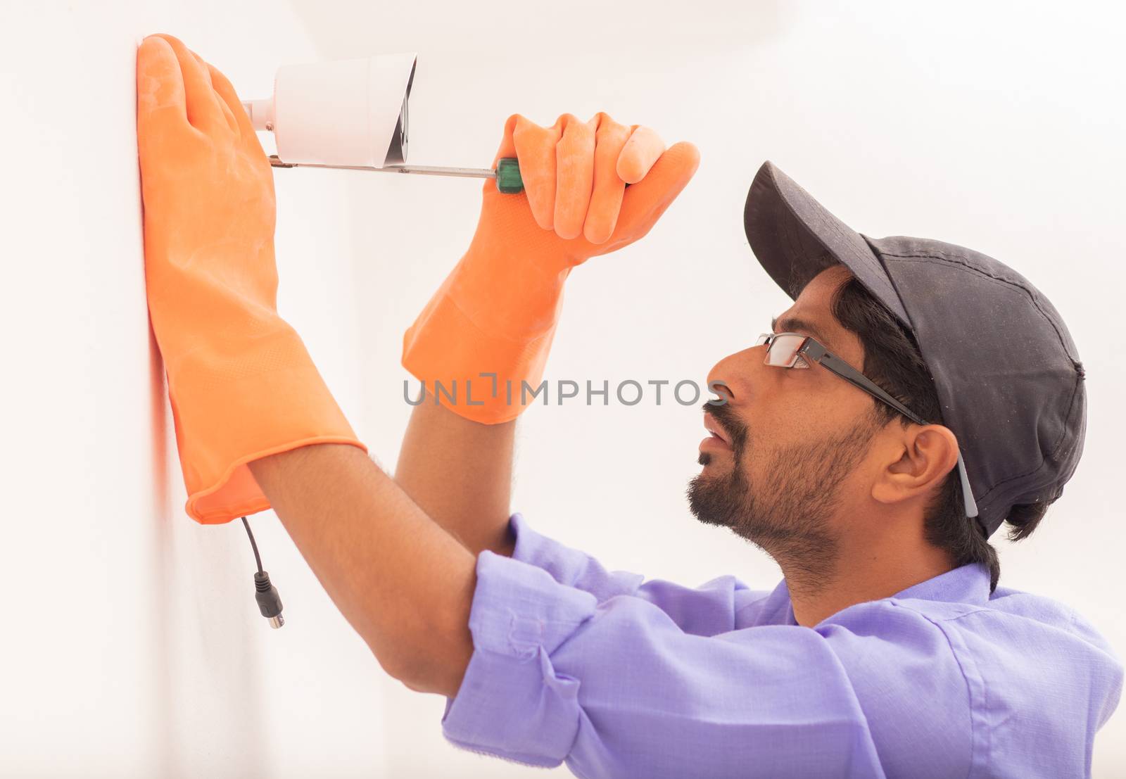 Technician man setup cctv camera security system on wall - Electrician installing video surveillance camera.