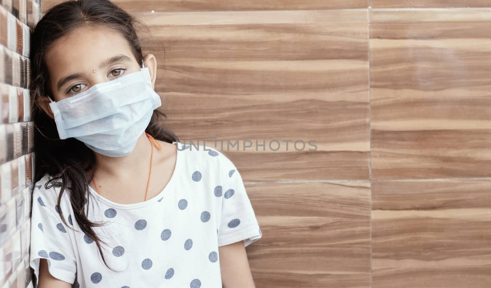 Concept of PTSD or post-traumatic stress disorder after covid-19 or coronavirus pandemic - Young teenager girl with medical mask wearing sat by leaning on well in sad, fear, or anxiety