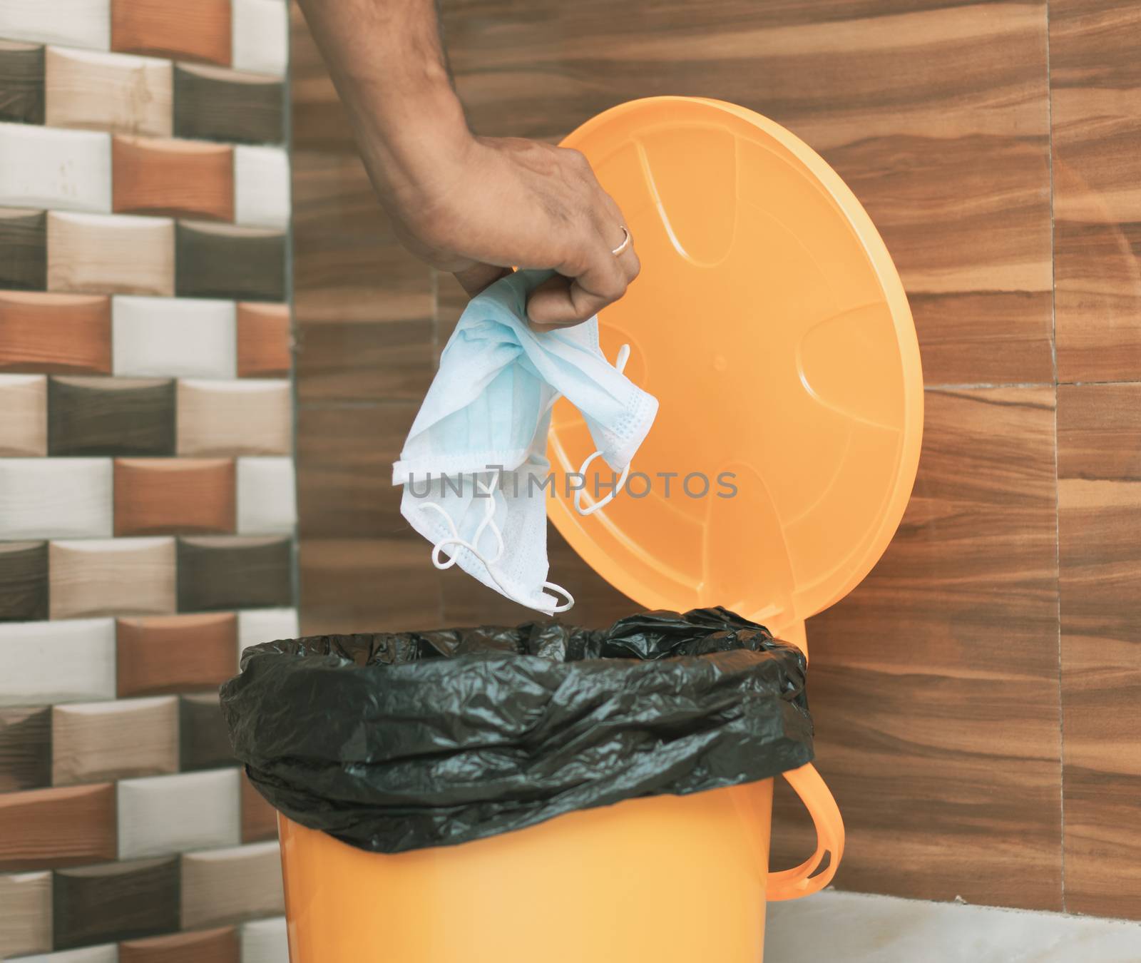 Hands throwing medical mask into closed bin - Covid-19, Coronavirus advice to discard or dispose medical mask to closed trash can after usage - concept showing to do hygiene practice