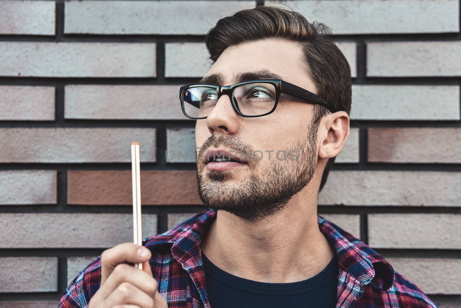 Portrait of handsome man in glasses and shirt isolated on brown brick wall.