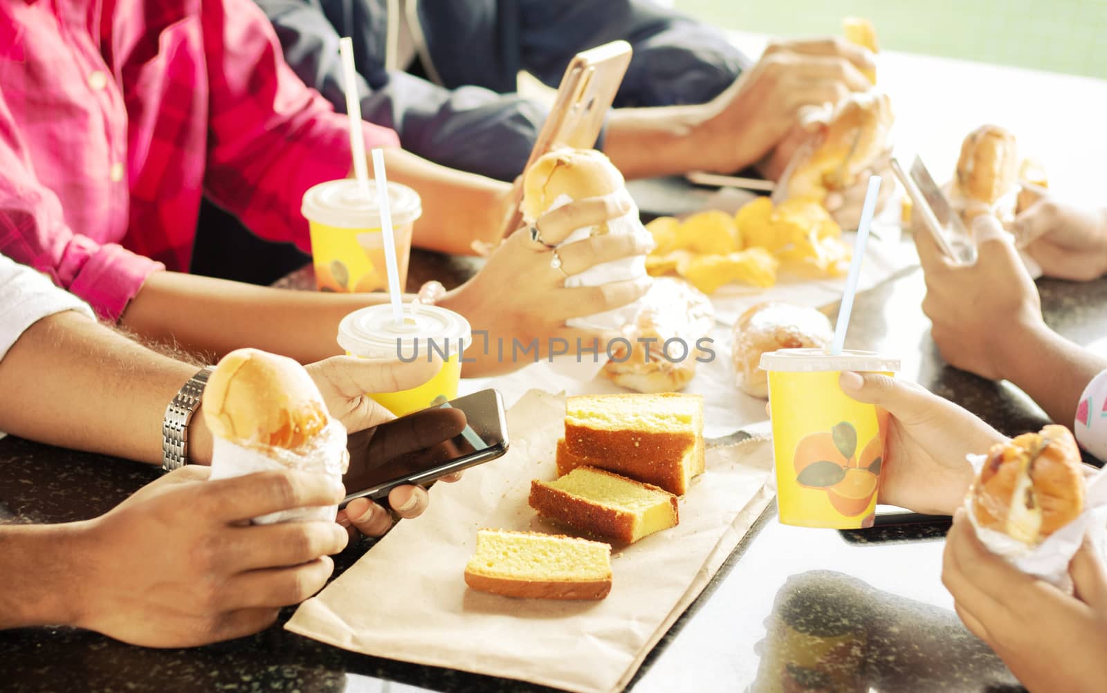 Group of people having snacks and busy on mobile together sitting at college restaurant - Concept of Friends Enjoying Dinning Eating, Happy meeting or having junk food and using mobile while eating by lakshmiprasad.maski@gmai.com