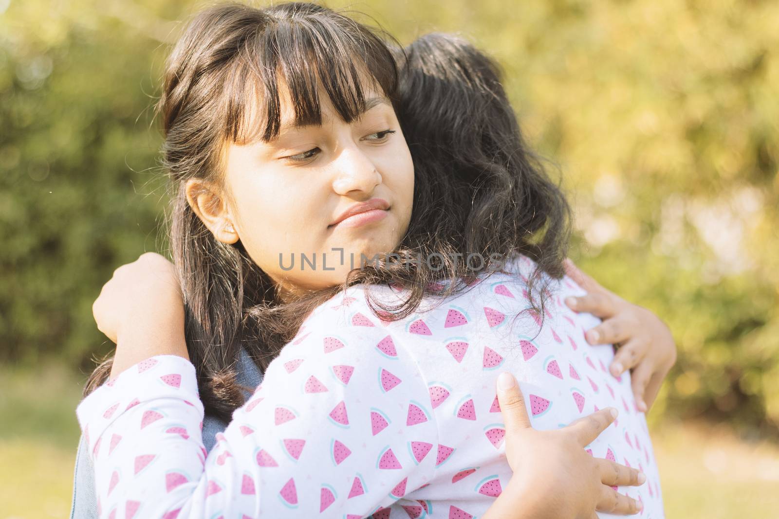Concept of fake hug, friendship, embracing or two faced - Young teenager Hypocritical girl embracing sad friend at park