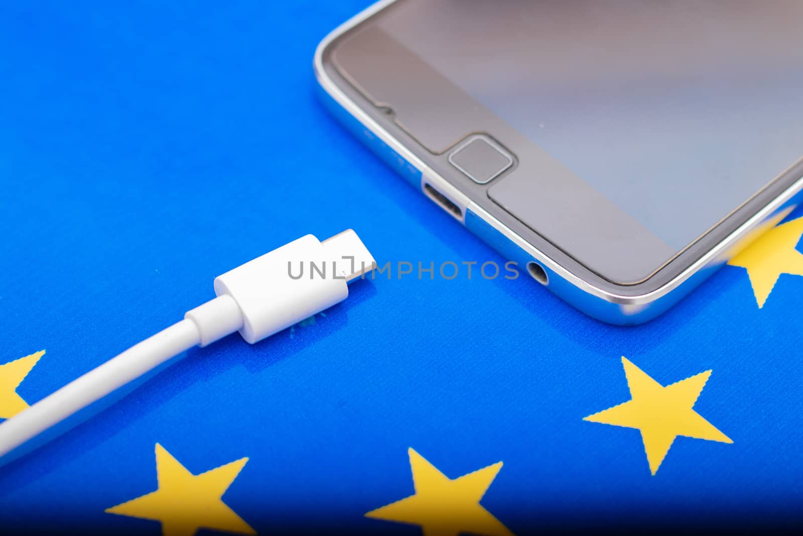 Close up Mobile phone Charger with USB Type - C cord on EU Flag.