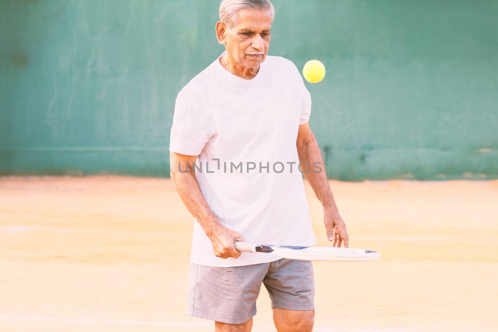 Elderly man playing tennis - Concept of healthy and fit old people - Senior player practicing tennis
