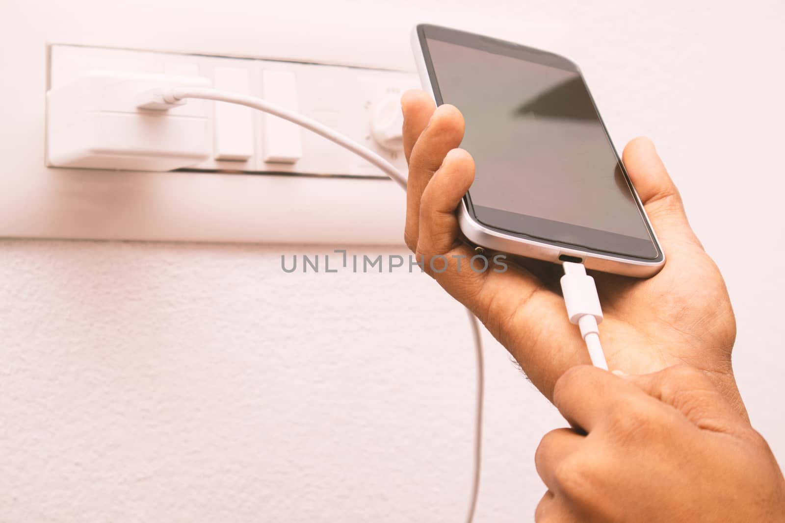 Maski, India 18,January 2020 - Hand holding smartphone and connecting USB type C charger cable to mobile for charging. by lakshmiprasad.maski@gmai.com