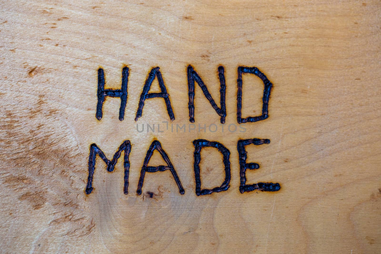 the word hand made handwritten on flat wooden background with electrical woodburner.