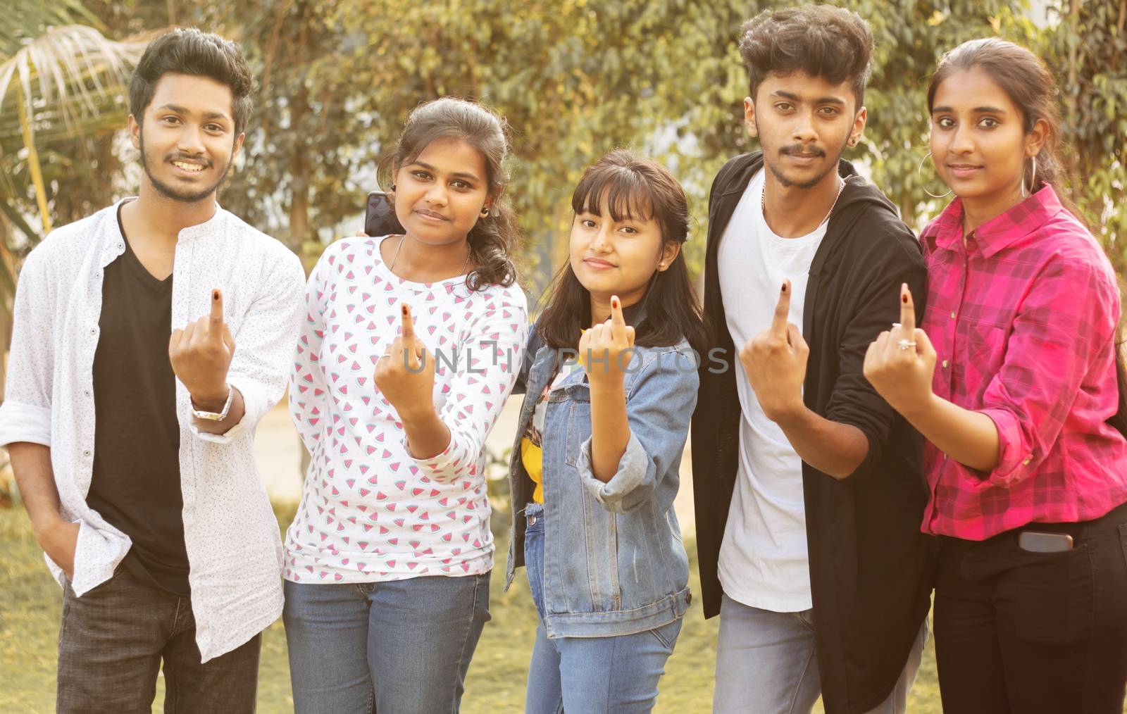 Group of teenager friends showing ink marked fingers outside polling station or booth after casting votes - Concept of Indian election or vote casting system