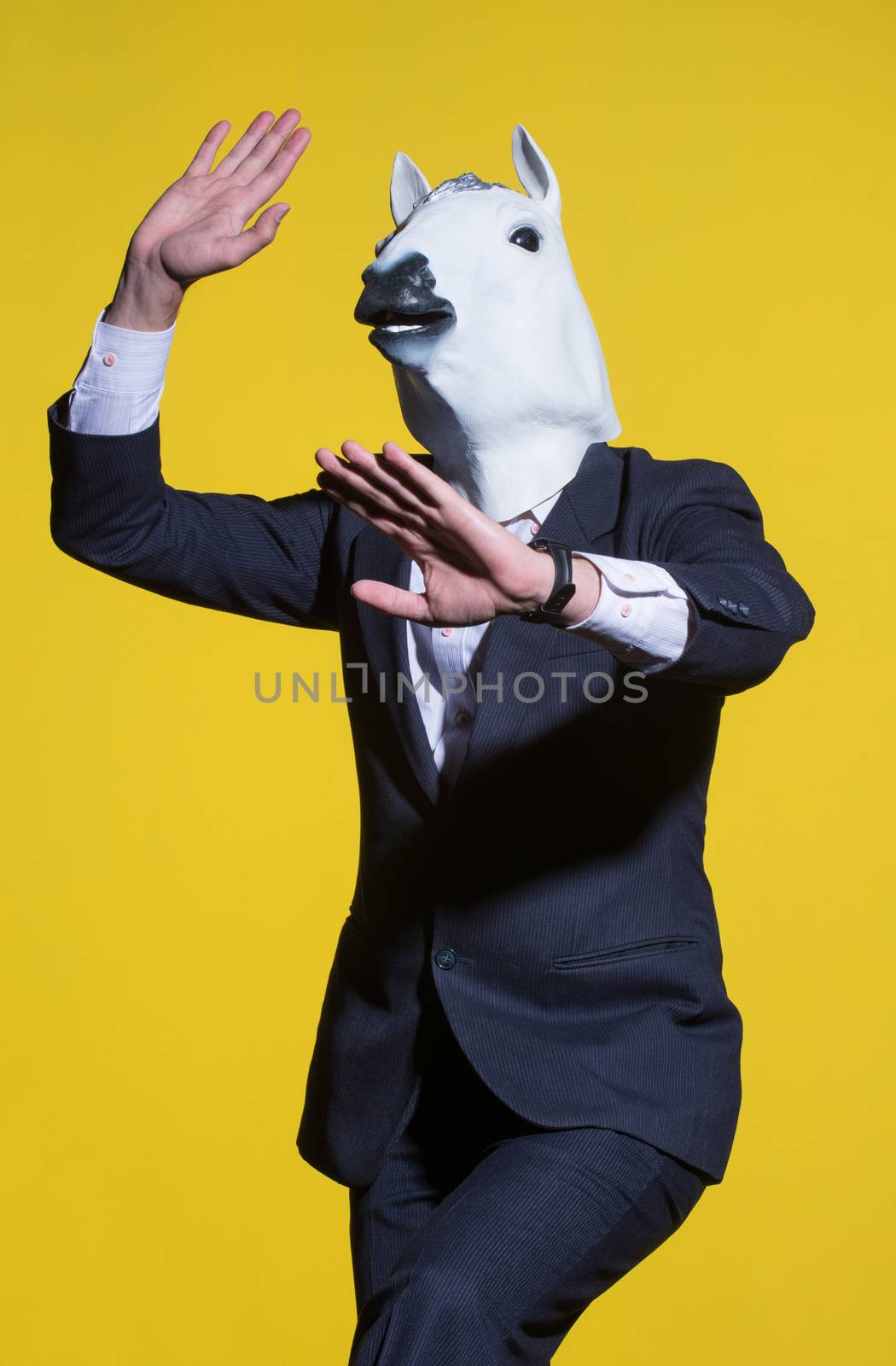 A man in a suit and a horse mask on a yellow background. Conceptual business background