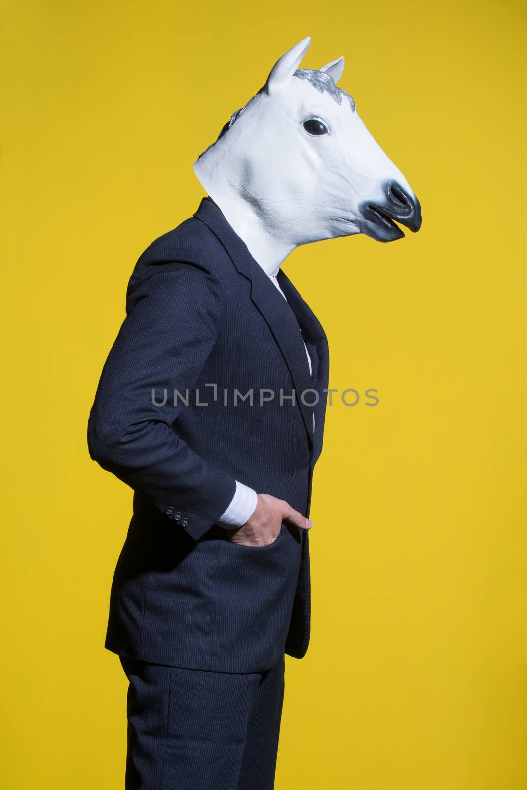 A man in a suit and a horse mask on a yellow background. Conceptual business background