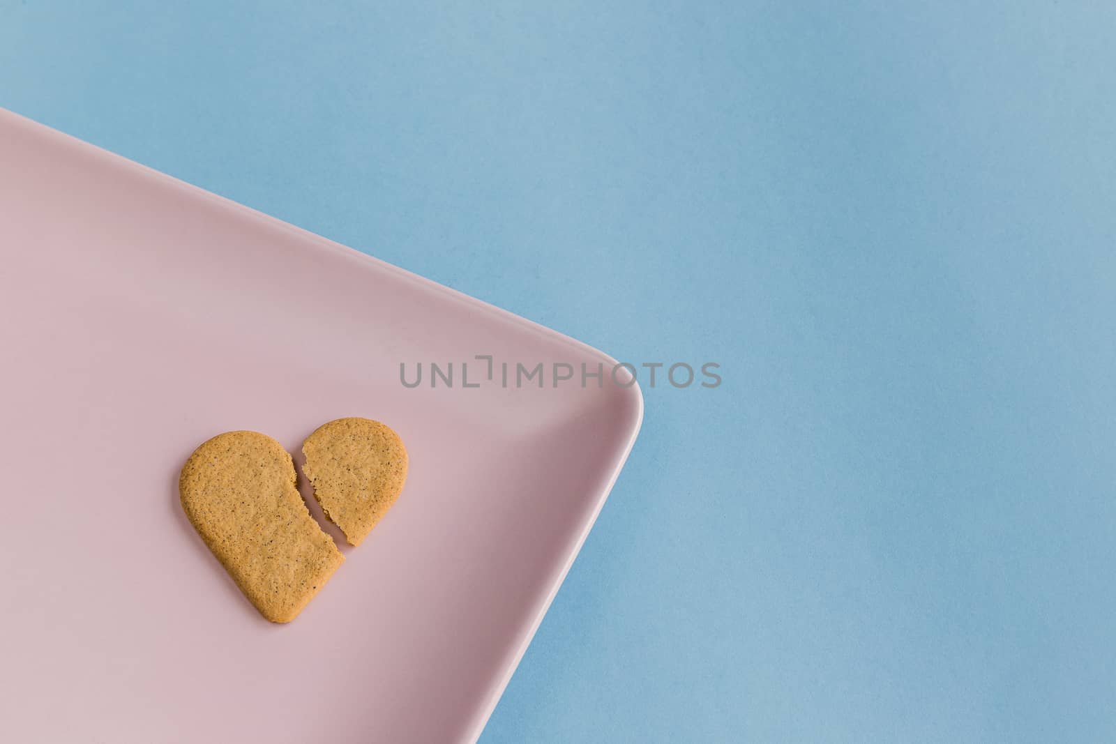 Broken heart. Heart broken cookie isolated on a pink tray. by JRPazos