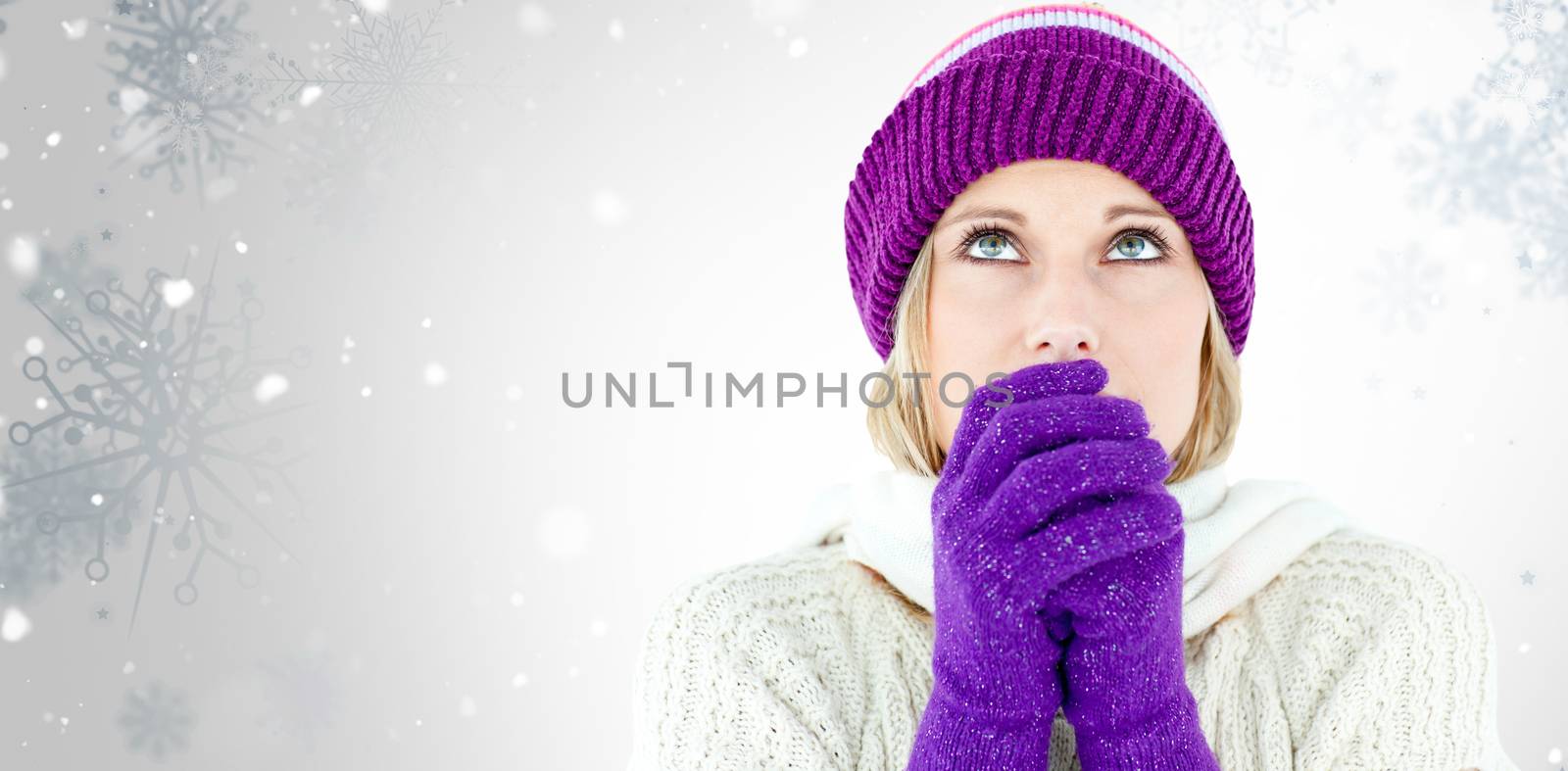 Freezing young woman wearing gloves looking upwards  against snowflake pattern