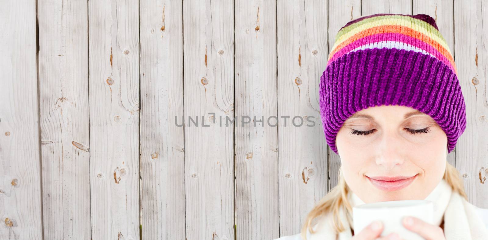 Composite image of delighted woman with a colorful hat and a cup in her hands by Wavebreakmedia