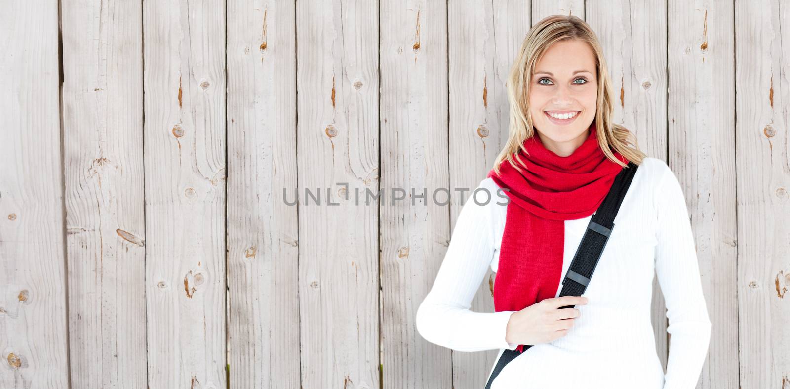 Portrait of a delighted student with scarf smiling at the camera against wooden background