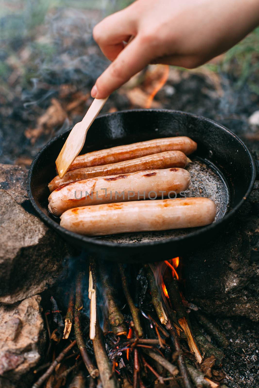 Roasting sausages in a frying pan over an open fire. Preparing f by Opikanets