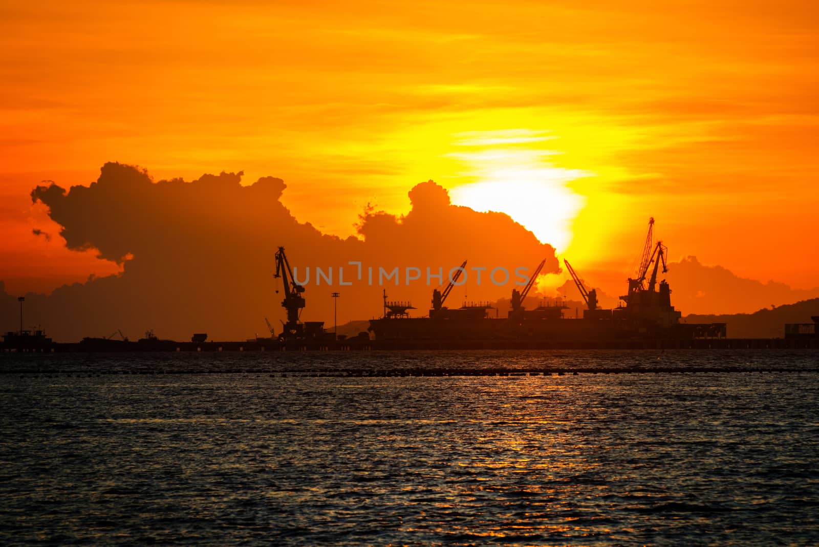 commercial dock with ship and cranes in sunset