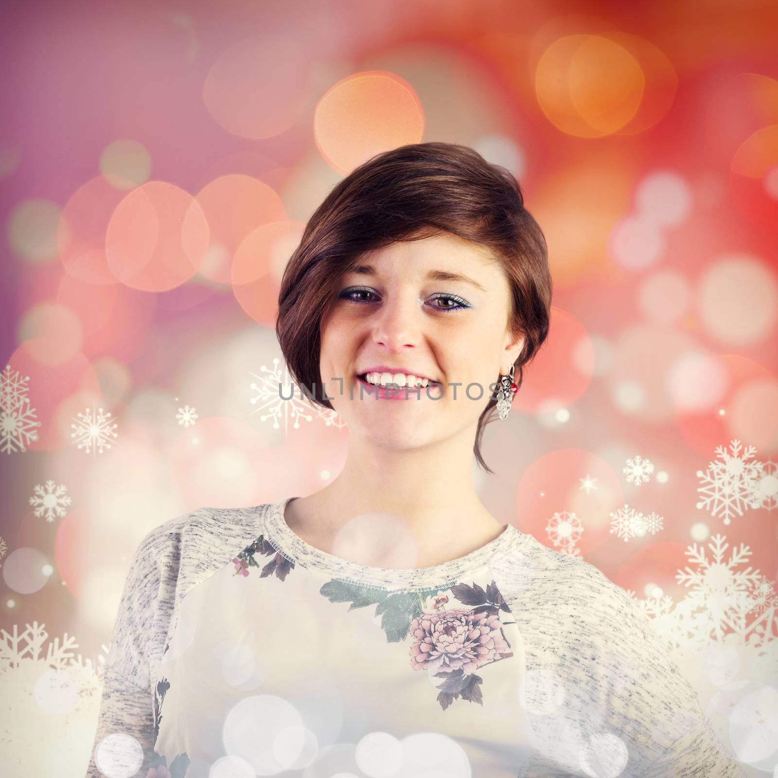 Pretty brunette smiling at camera against snowflake pattern