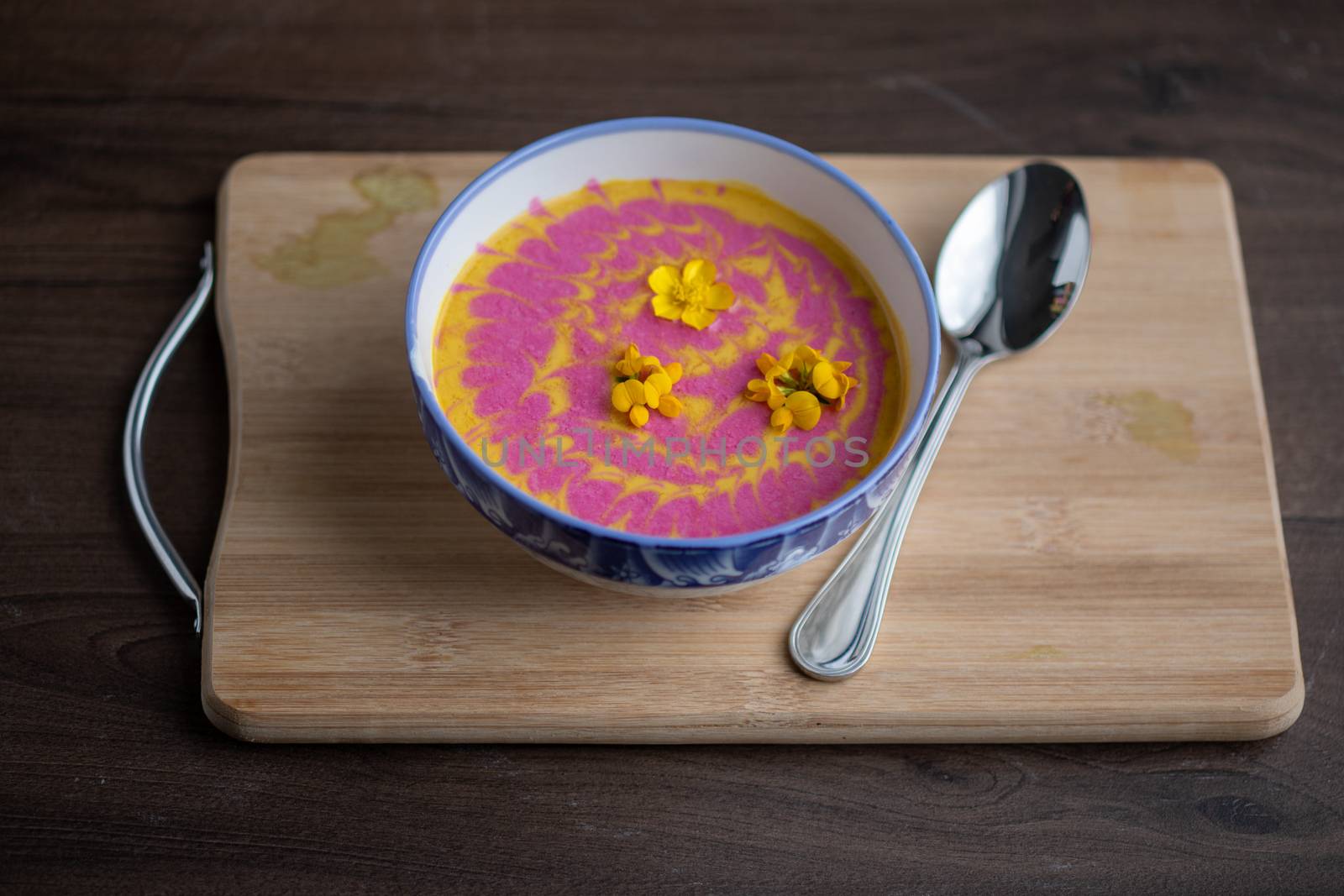 Vegetarian cream pumpkin and beet mix soup decorated with fresh yellow flowers delicious and healthy food