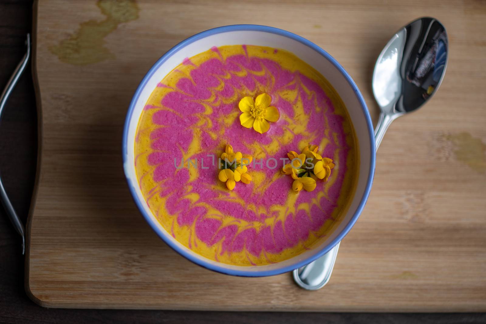 Vegetarian cream pumpkin and beet mix soup decorated with fresh yellow flowers delicious and healthy food