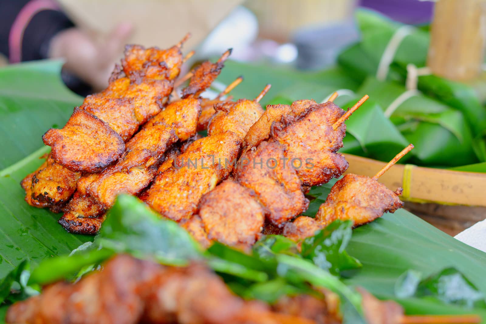 Thai street food. Delicious Chicken mixed with Thai herb grilled with wooden stick on green banana leave. Reduce plastic concept.