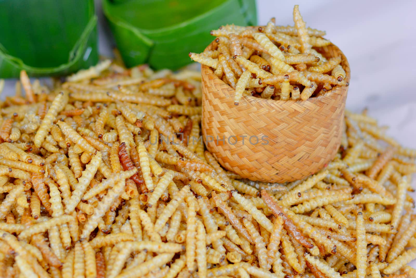 Thai street food. Deep fried insects (bamboo worm) in wooden basket sell in local market of Thailand. High protiene.