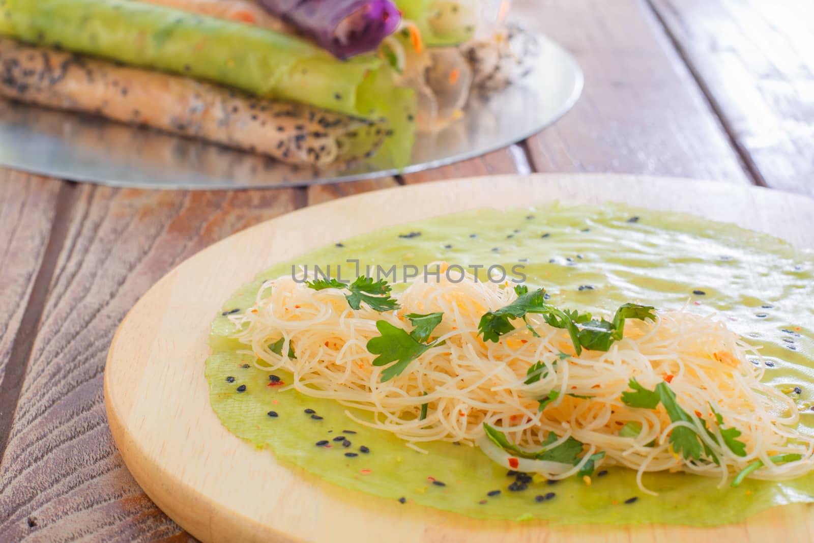 Thai food. Vermicelli rice wrap with coriander and spicy sauce on round wooden tray.